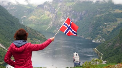 Sticker - Tourist woman holding norwegian flag, enjoying Geirangerfjord fjord view with large cruise ship. Tourism, travel for relaxation and sightseeing