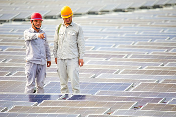 Two Asian senior engineers standing on the surface of a floating photovoltaic solar base are doing research