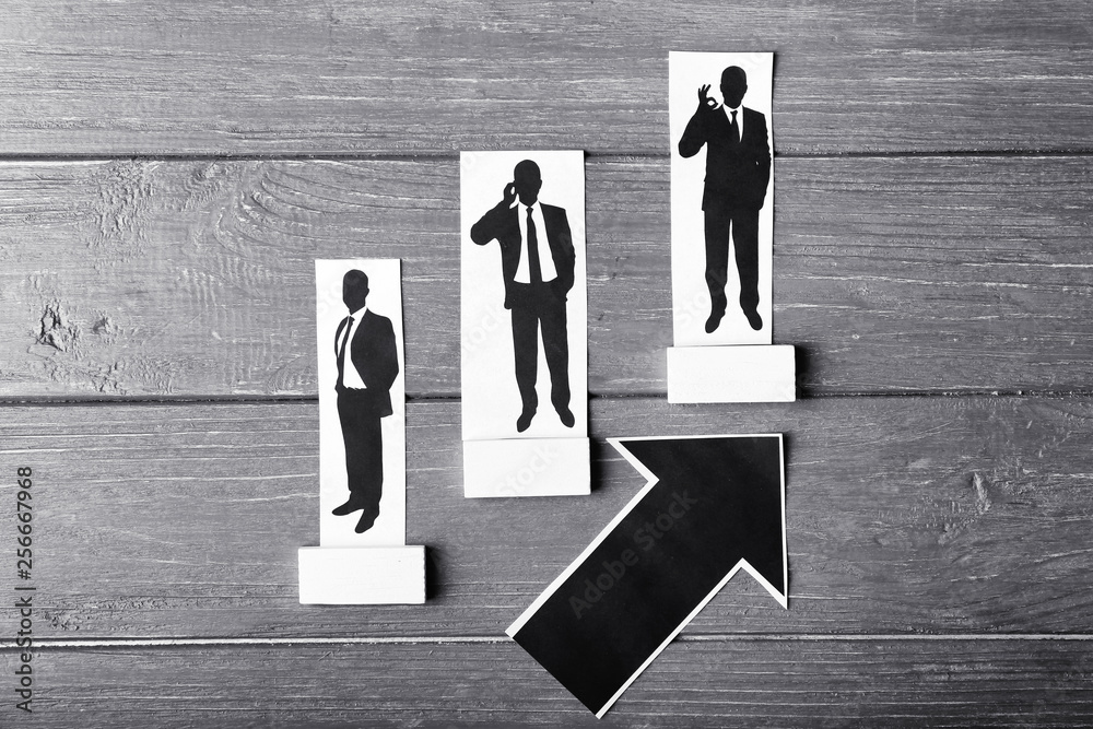 Pointing up arrow with human figures on wooden table. Concept of career growth