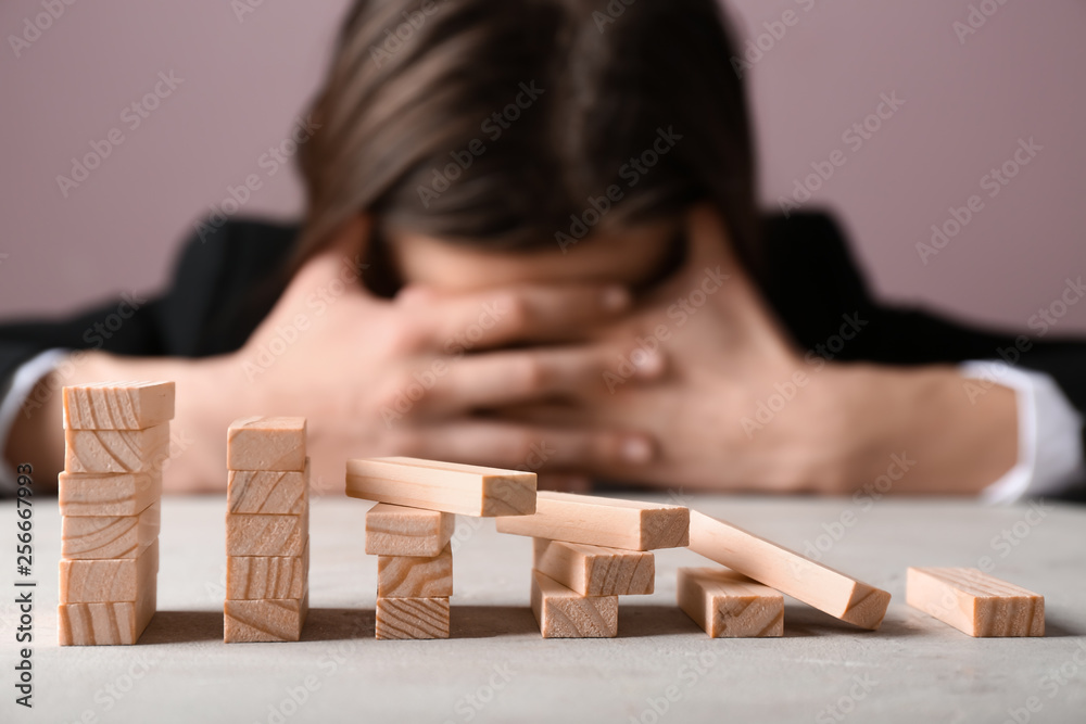 Stressed woman with destroyed blocks on light table. Concept of career failure