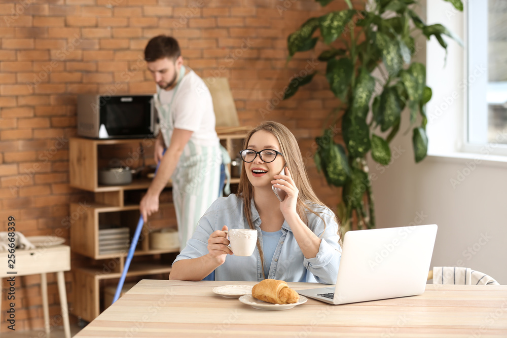 Busy wife working while her husband doing chores at home