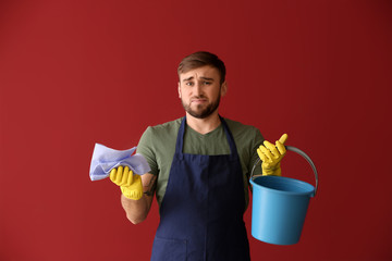 Poster - Disappointment lazy man with cleaning supplies on color background