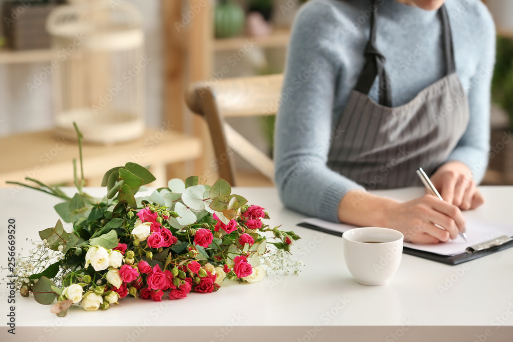 Beautiful female florist working at table in shop