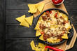 Tasty Mexican dish with nachos on table