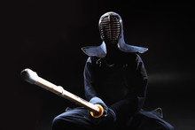 Kendo Fighter In Armor Holding Bamboo Sword On Black