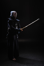 Full Length View Of Kendo Fighter In Armor Practicing With Bamboo Sword On Black