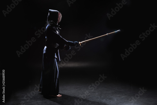Obrazy Kendo  widok-z-boku-wojownika-kendo-w-zbroi-cwiczacego-z-bambusowym-mieczem-na-czarno