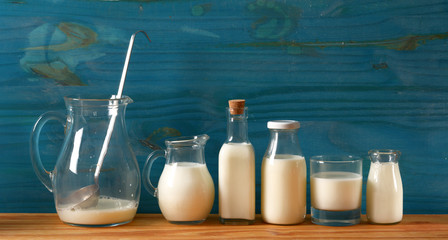 Wall Mural - fresh milk in glass containers with blue wooden background - closeup