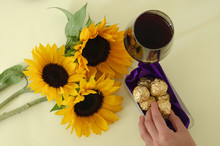 Three Sunflowers With Chocolates And Wine Glass. Top View.