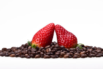 Two dancing strawberries among brown grains of aromatic coffee on a neutral white background