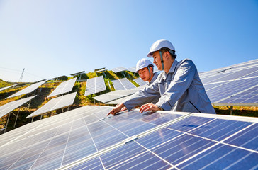 Two Asian engineers are testing the solar photovoltaic base at the top of the mountain