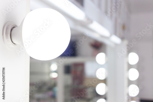 Leinwand Poster  Beautiful stylish long hair curly blonde woman with bright hollywood makeup in dark blue shiny dress sitting on table near professional lighting mirror looking away with passion