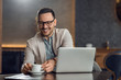 © Goran - Happy mid adult  businessman having a coffee break in a cafe and working on computer.