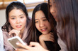 © themorningglory - Group of cheerful women using smartphone shopping online together