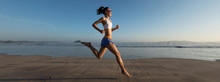 Young Fitness Woman Running At Sunrise Beach