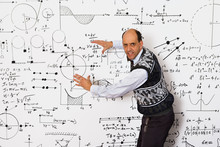 Middle Aged Caucasian Mathematician Explaining Equations On A White Wall
