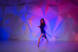 Woman dancing on the background of a beautiful multicolored wall. Sexy slim lonely girl with long black hair in a beautiful dark blue dress. bright colorful geometry background in dancing school