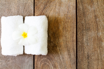 White towel with white flower on vintage wooden background, spa concept