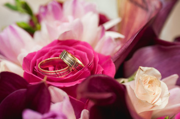 Detail of a bouquet of roses and wedding rings.