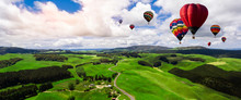 Beautiful Panoramic Nature Landscape Of Countryside Mountains With Colorful High Hot Air Balloons Festival In Summer Sky. Vacation Travel Panorama Background.