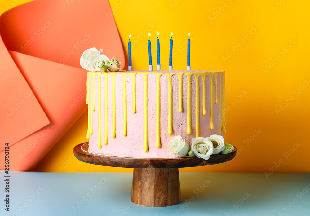 Tasty cake with burning candles on color background