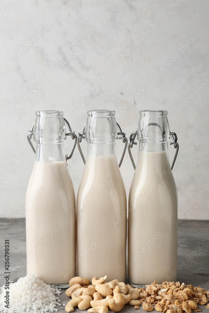 Assortment of tasty vegan milk on grey table