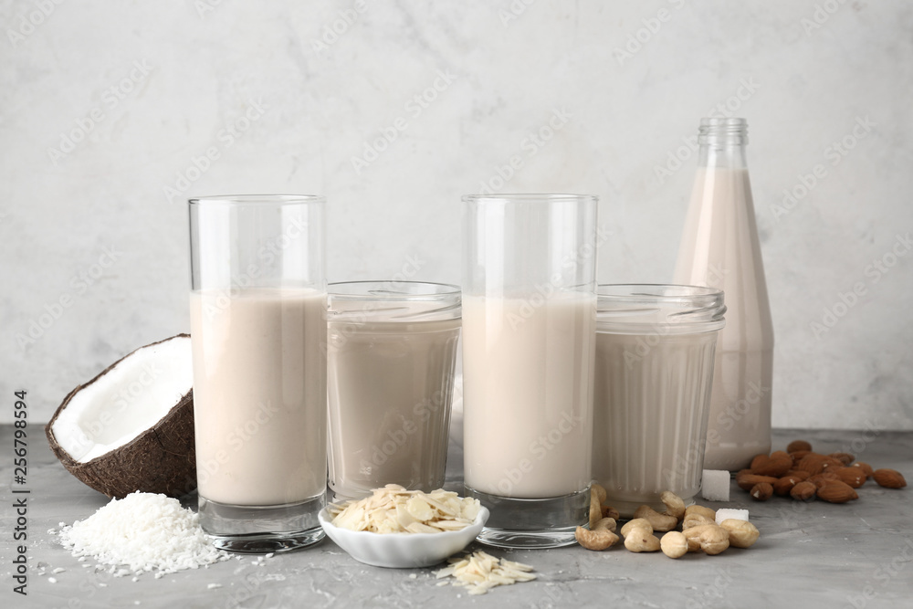 Assortment of tasty vegan milk on grey table
