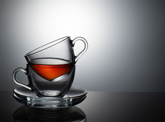 The tea set consists of two glass bowls and a saucer on a gray background.