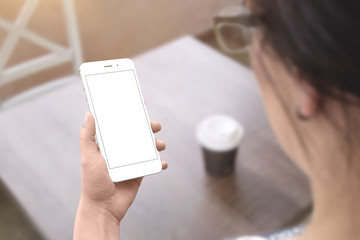 Poster - Woman hold white smart phone with isolated screen for mockup. Coffee shop table in background.