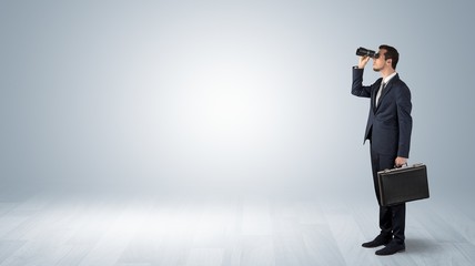 Wall Mural - businessman looking forward with binoculars in an empty space