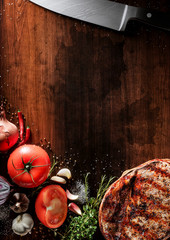 Wall Mural - Fresh beef steak on the old wood desk. Around are fresh tomatoes in drops of water, sweet and spicy peppers, greens, spices, salt and black pepper. Ideal for the restaurant menu or for intro video