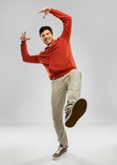 Sticker - motion and people concept - smiling young man in red hoodie stepping up over grey background