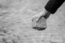 closeup of granit cobble in hand of anarchist man in the street