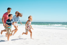 Happy Family Running On Beach