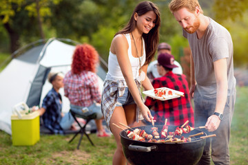 Wall Mural - Guy and lassie putting grilled skewers on plate