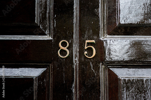 Cuadros en Lienzo House number eighty five with the 85 in bronze lettering on a black wooden paint