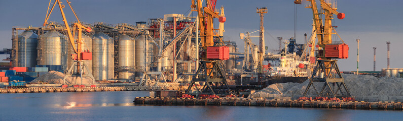 Wall Mural - Loading grain to the ship in the port. Panoramic view of the ship, cranes, and other infrastructures of the port.