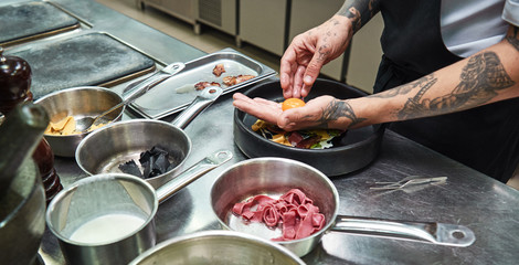 Wall Mural - Special ingredient. Cropped image of chef hands with several tattoos adding a yolk to italian pasta