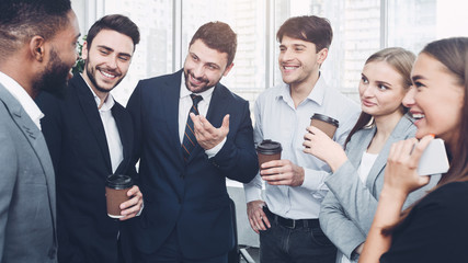 Happy colleagues talking, having coffee break in office