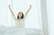 white dress asian beautiful woman stretching morning wake up bedroom with white curtain background lifestyle home concept