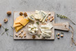 Assortment of cheese with nuts on wooden board