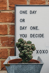One day or day one motivational quote on a white board against brick wall.