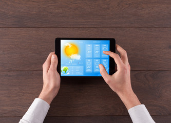 Wall Mural - man hand checking weekly weather forecast on tablet