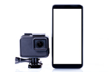 A modern video sports camera next to a black smartphone with screen in blank isolated