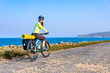 Adult attractive female cyclist riding her mountain bike by the ocean coast and looking back at the camera.