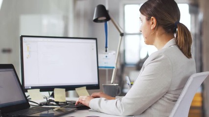 business, programming and technology concept - female programmer with computer working at office