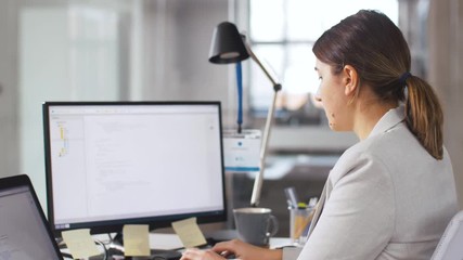 business, programming and technology concept - female programmer with computer working and giving folder to her colleague at office
