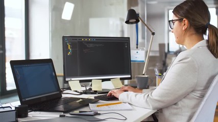 business, programming and technology concept - female programmer with script on computer screen working and drinking coffee at office