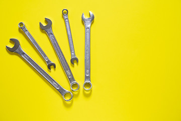 Spanner Set Arc. Silver coloured spanners lying side by side in yellow background.