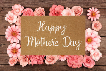 Happy Mothers Day greeting card with frame of rustic pink paper flowers over a dark wood background